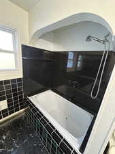 Full bathroom featuring tiled tub and tile walls