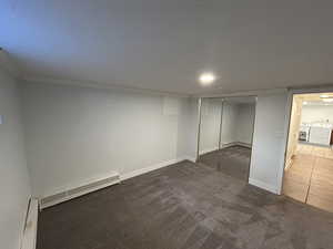 Unfurnished bedroom featuring a baseboard heating unit, carpet flooring, a closet, tile patterned flooring, and baseboard heating