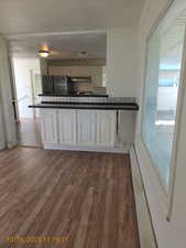 Kitchen featuring dark countertops, dark wood-style floors, decorative backsplash, freestanding refrigerator, and baseboard heating