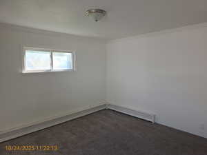 Carpeted spare room featuring baseboard heating, crown molding, and a baseboard heating unit