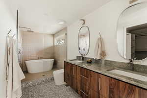 Full bath featuring double vanity, walk in shower, a freestanding tub, and light tile patterned floors