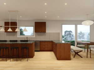 Kitchen with hanging light fixtures, a breakfast bar area, brown cabinetry, light wood-style flooring, and tasteful backsplash