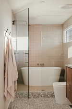 Bathroom with a freestanding bath, vanity, tile walls, tile patterned flooring, and walk in shower