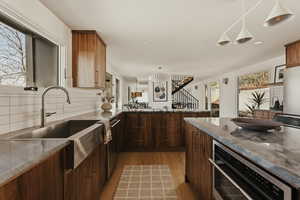 Kitchen with decorative light fixtures, a peninsula, appliances with stainless steel finishes, light wood-style flooring, and decorative backsplash