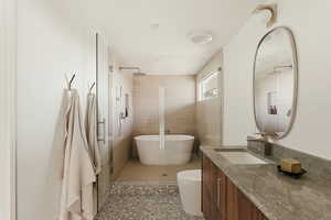 Bathroom with vanity, a tile shower, a freestanding bath, and dark tile patterned floors