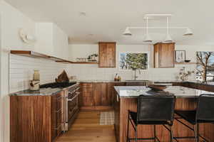 Kitchen featuring open shelves, high end range, a kitchen island, a breakfast bar area, and light wood-style flooring