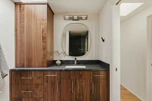 Bathroom featuring vanity, light wood-style flooring, and a skylight