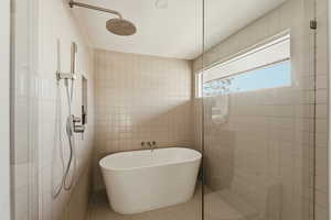 Bathroom featuring walk in shower, a soaking tub, tile patterned floors, and tile walls