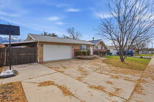 View of front facade with concrete driveway, an attached garage, a shingled roof, and a carport