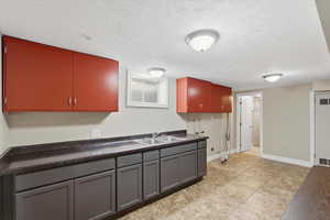 Kitchen featuring dark countertops, a textured ceiling, light tile patterned floors, and gray cabinetry