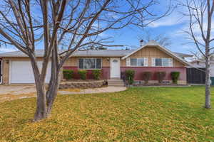 Ranch-style home with brick siding, an attached garage, board and batten siding, and driveway