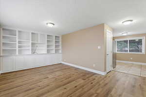 Spare room featuring light wood finished floors, a textured ceiling, and built in features