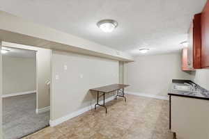 Finished below grade area featuring a textured ceiling and light tile patterned flooring