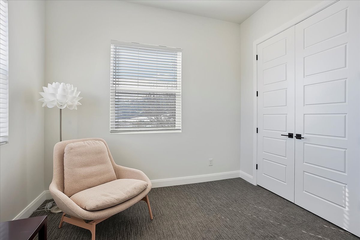 Living area with baseboards and dark colored carpet