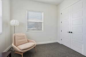 Living area with baseboards and dark colored carpet