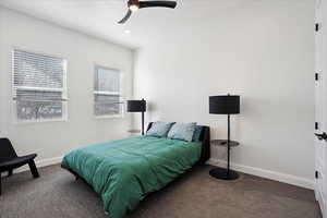 Bedroom with dark colored carpet, ceiling fan, and a textured ceiling