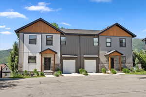 View of front facade with stone siding, concrete driveway, and a garage