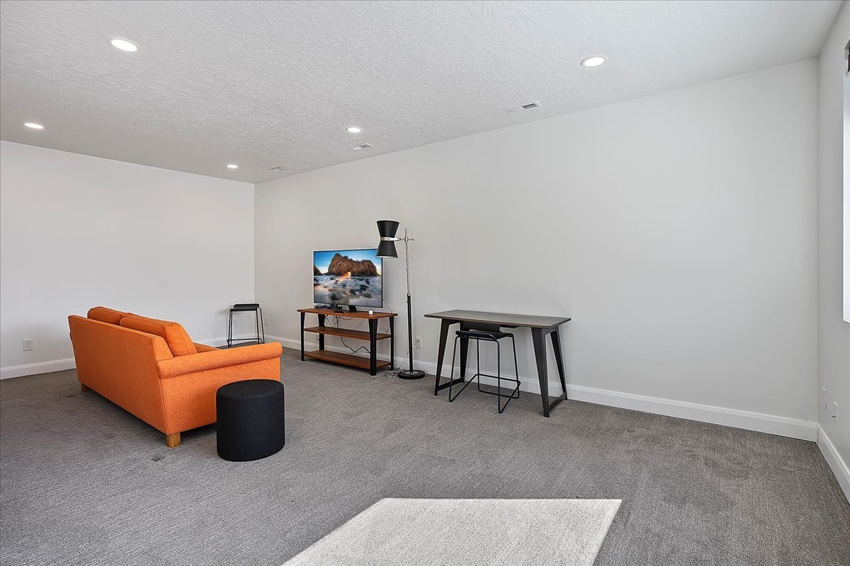Living area featuring carpet, recessed lighting, and a textured ceiling