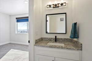 Bathroom featuring vanity, light colored carpet, and a textured ceiling