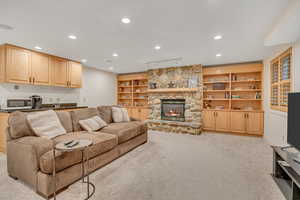 Basement family room with built in features, light carpet, a stone fireplace, recessed lighting, and rail lighting