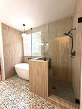 Main Level Primary Bathroom with a freestanding tub, a shower stall, and tile patterned flooring