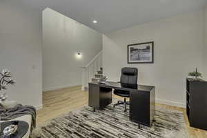 Office area with light wood-style floors and recessed lighting