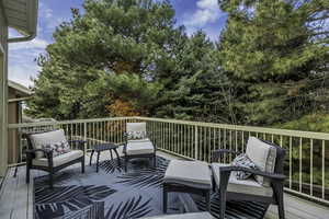 Deck with outdoor lounge area and view of wooded area