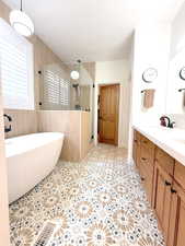 Main Level Primary Bathroom featuring a soaking tub, a stall shower, vanity, and light tile patterned floors