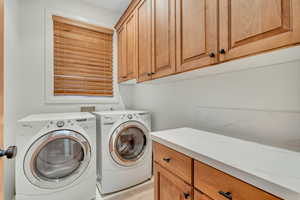 Main Level Laundry room featuring independent washer and dryer, cabinet space, and light tile patterned floors