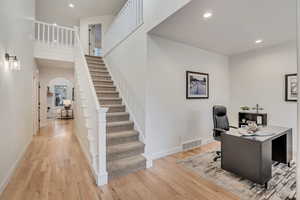 Office space with recessed lighting, arched walkways, and light wood-style floors
