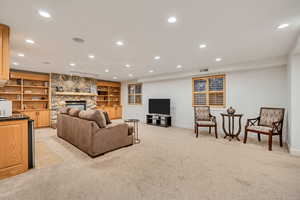 Basement family room with built in shelves, recessed lighting, light carpet, and a fireplace