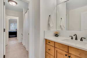 North vanity of Jack-n-Jill Full bathroom featuring vanity, a shower with curtain, light tile patterned floors, and connected bathroom