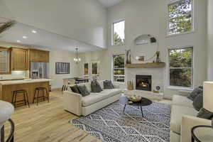 Living room featuring a chandelier, a towering ceiling, light wood-type flooring, a fireplace, and recessed lighting