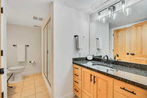 Basement Bathroom featuring vanity, light tile patterned floors, a stall shower, and a textured ceiling
