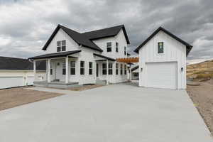 Modern inspired farmhouse featuring board and batten siding, a garage, a shingled roof, covered porch, and driveway