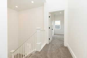 Hall featuring an upstairs landing, carpet, and recessed lighting