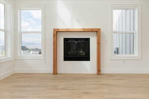 Unfurnished living room with a glass covered fireplace, wood finished floors, and healthy amount of natural light
