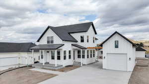 Modern farmhouse featuring board and batten siding, roof with shingles, concrete driveway, a garage, and a standing seam roof