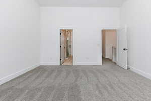 Unfurnished bedroom with light carpet and a towering ceiling