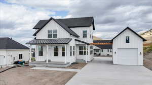 Modern inspired farmhouse featuring board and batten siding, driveway, and a shingled roof