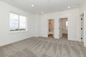 Unfurnished bedroom featuring light colored carpet, recessed lighting, and connected bathroom