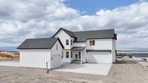 Modern farmhouse featuring a shingled roof, board and batten siding, an attached garage, driveway, and a mountain view