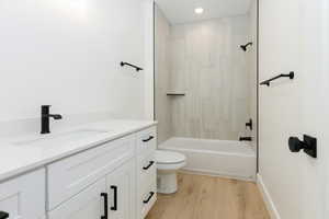 Bathroom with vanity, light wood-style flooring, tub / shower combination, and recessed lighting