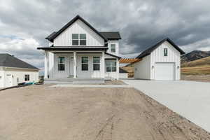 Modern inspired farmhouse featuring board and batten siding, a porch, driveway, and an outbuilding