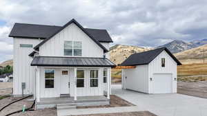 Modern inspired farmhouse featuring a mountain view, board and batten siding, a shingled roof, and an outbuilding