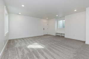 Empty room with light colored carpet and recessed lighting