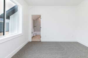 Unfurnished bedroom with light colored carpet and ensuite bath