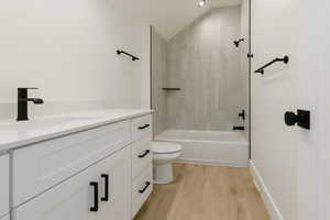 Full bath featuring vanity, light wood-style flooring, shower / tub combination, and lofted ceiling
