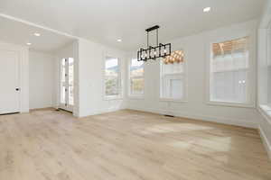 Unfurnished dining area featuring a chandelier, light wood-type flooring, and recessed lighting