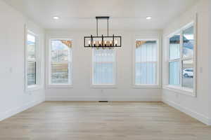 Unfurnished dining area with a chandelier, light wood-type flooring, and recessed lighting